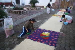 Personas elaborando un tapete de acerrín coloreado para la celebración del jueves de Corpus Cristi en Huiramba, Michoacán.