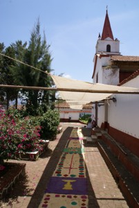 Parte del espacio que se recorrió en la procesión de jueves de Corpus Cristi en el atrio del Conjunto Parroquial del pueblo de Huiramba en el año 2009. Destacan la manta y el tapete de acerrín coloreado en el trayecto.